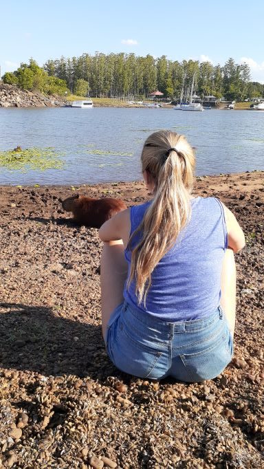 mujer mirando a los carpinchos frente al lago