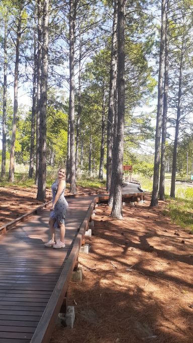 mujer posando sobre pasarela de maera rodeada de pinos en el ecoparque de Concordia